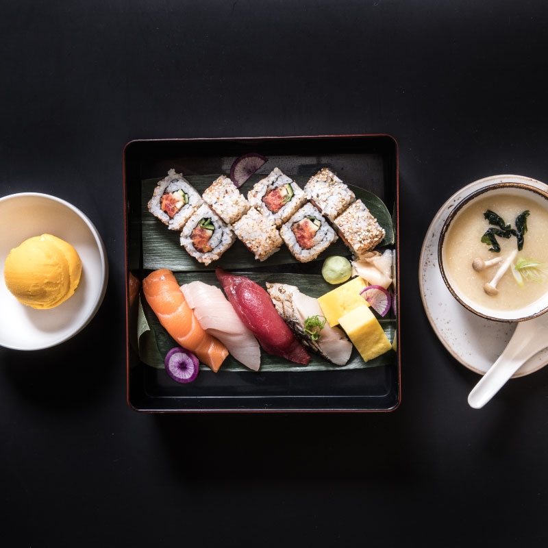 photo of sushi in pick up box with oranges